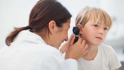 Photo of a girl having her ear examined by a doctor