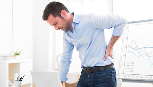 Photo of a man with back pain at a desk