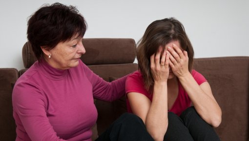 Photo of a mother comforting her daughter on sofa