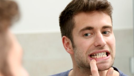 Photo of a man looking at his teeth in the mirror