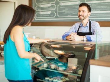 Photo of a woman choosing a piece of cake at a café 