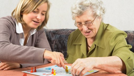 Photo of an older woman playing a board game with a younger woman