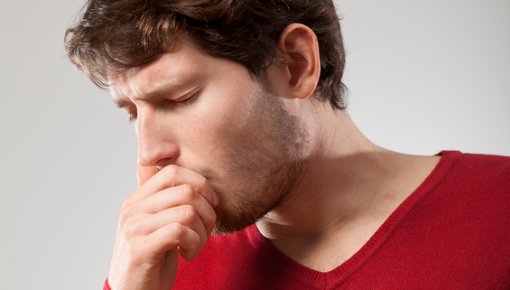 Photo of a man coughing and holding his chest