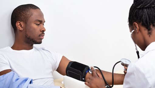 Photo of a woman measuring a man’s blood pressure