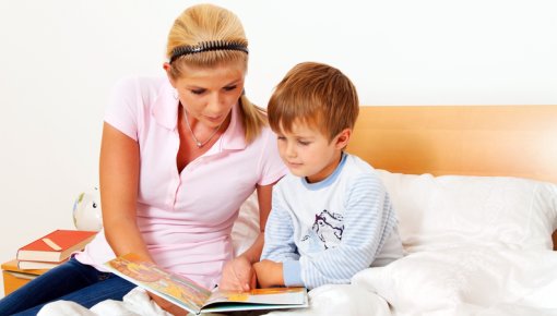 Photo of a mother looking at a book with her young son