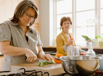 Photo of two women in a kitchen cutting vegetables