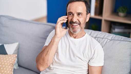 Photo of a man on the phone sitting on a sofa