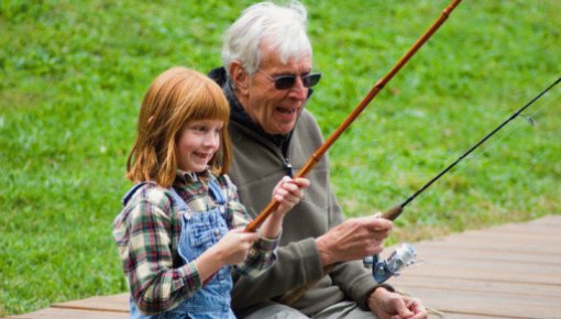 Photo of an elderly man fishing with his granddaughter