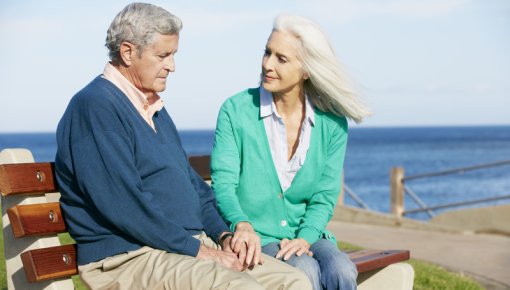 Photo of an elderly couple sitting on a bench by the sea