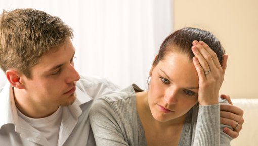 Photo of a man comforting a woman next to him on the couch