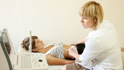 Photo of a doctor doing an ultrasound examination of a woman's belly