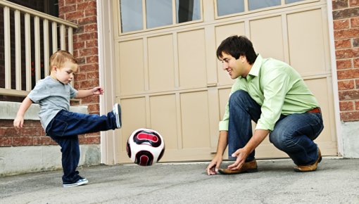 Photo of a father and son playing with a ball