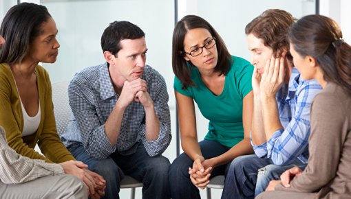 Photo of group of adults sitting on chairs in a circle
