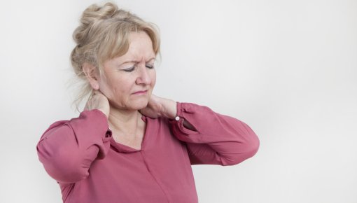 Photo of a woman holding the back of her neck in pain