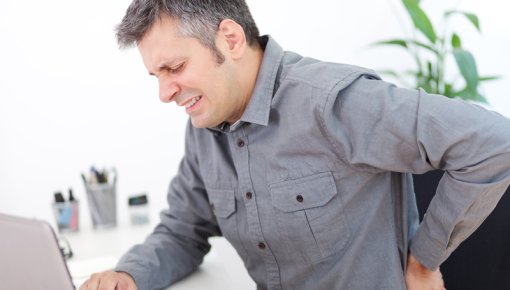 Photo of a man holding his lower back in pain