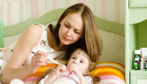 Photo of a woman taking her daughter’s temperature