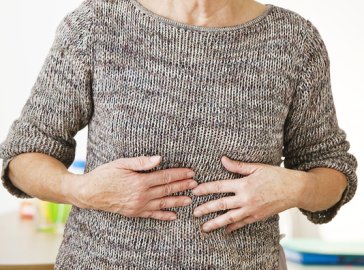 Photo of an elderly woman holding her belly in pain
