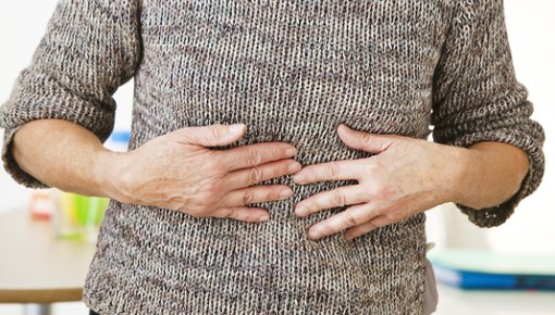 Photo of a woman holding her upper belly in pain