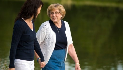 Photo of two women walking near a lake