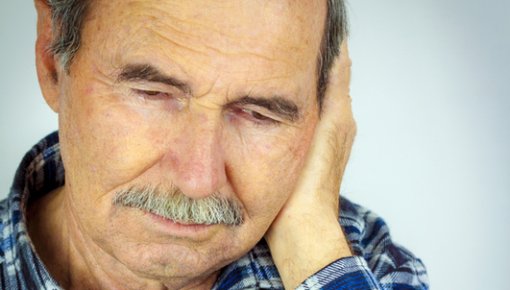 Photo of an older man holding his ear