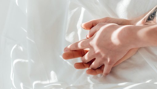 Photo of a couple's crossed hands in bed