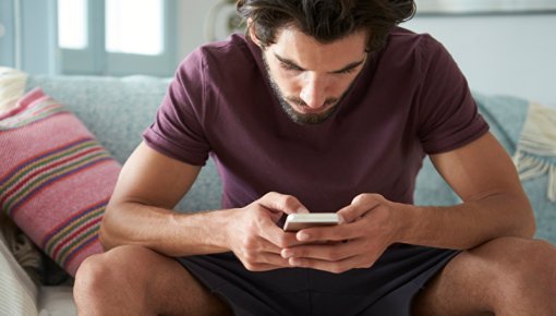 Young man sitting on couch with smartphone