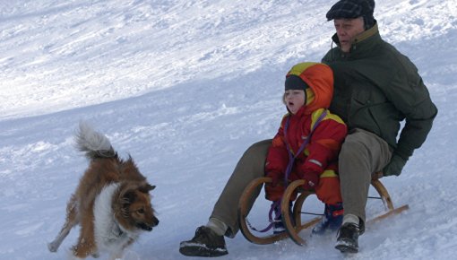 Photo of a grandfather and grandchild playing in the snow