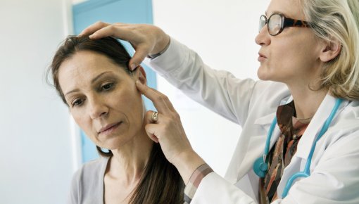 Photo of a doctor examining the side of a woman's face