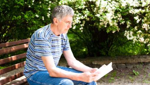 Photo of man reading on a park bench