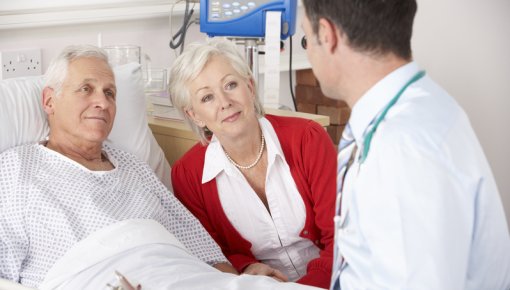 Photo of an older man in a hospital bed talking to a doctor