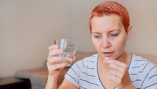 Photo of a woman taking tablets with a glass of water
