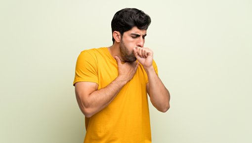 A young man coughing while standing