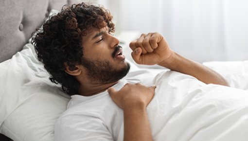Young man coughing in bed