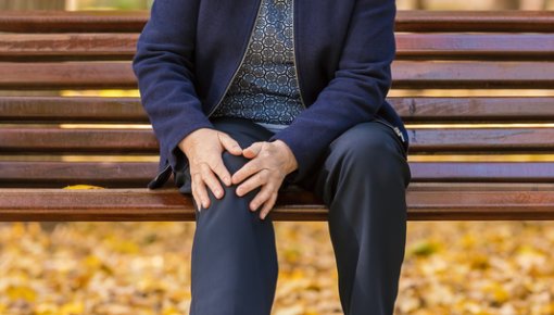 Photo of a woman with knee pain sitting on a bench