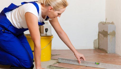 Photo of a woman laying floorboards while kneeling