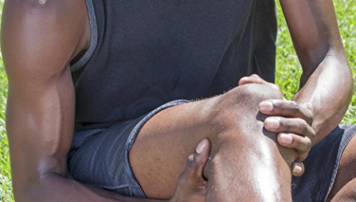 Photo of an athletic man holding his knee in pain