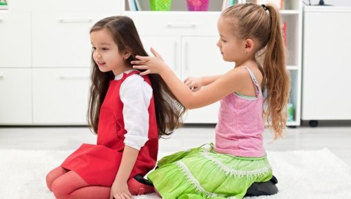 Photo of a girl brushing another girl's hair