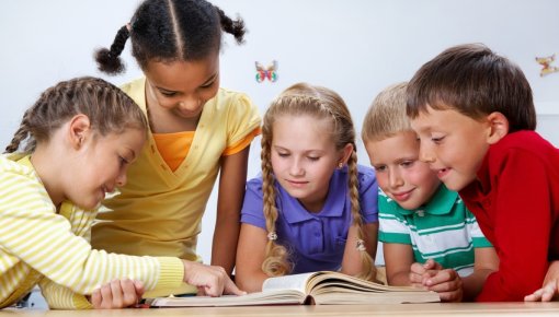 Photo of schoolchildren huddled around a book
