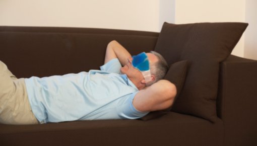 Photo of man with a migraine on a sofa