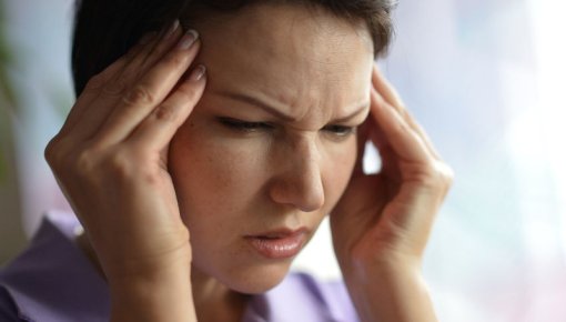 Photo of woman holding her head in pain