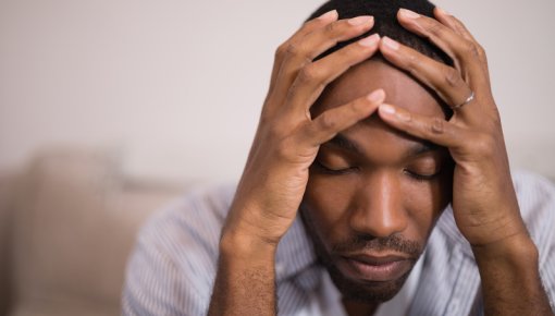 Photo of a man holding his head with his eyes closed