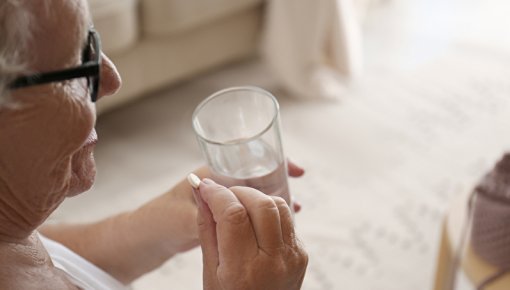 Elderly lady taking a tablet with a glass of water