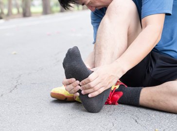 Photo of a runner holding his foot in pain