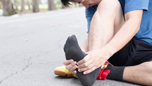 Photo of a runner holding his foot in pain