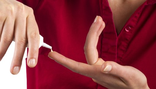 Photo of a woman putting cream on her fingertip