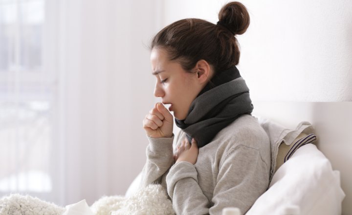 Photo of a woman coughing in bed