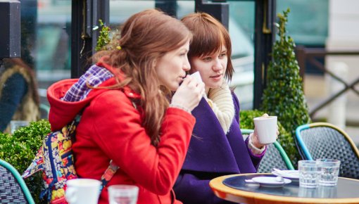 Photo of two women sitting outside a café