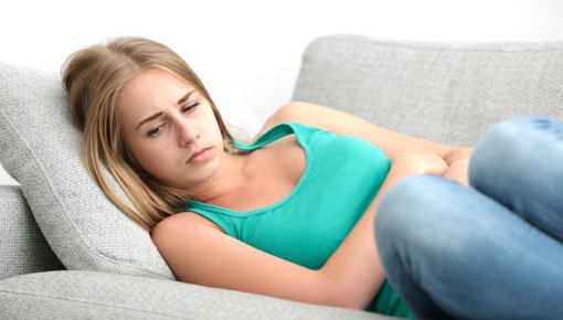 Photo of a young woman holding her tummy in pain