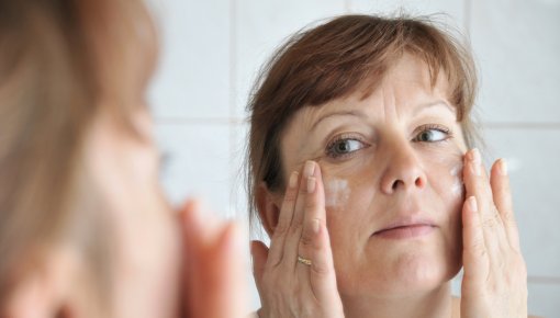 Photo of a woman applying cream to her face