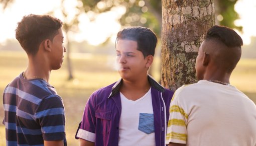 Photo of three teenage boys talking outdoors
